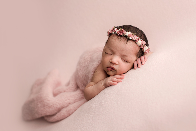 Newborn Girl with Floral Headband on Pink Background